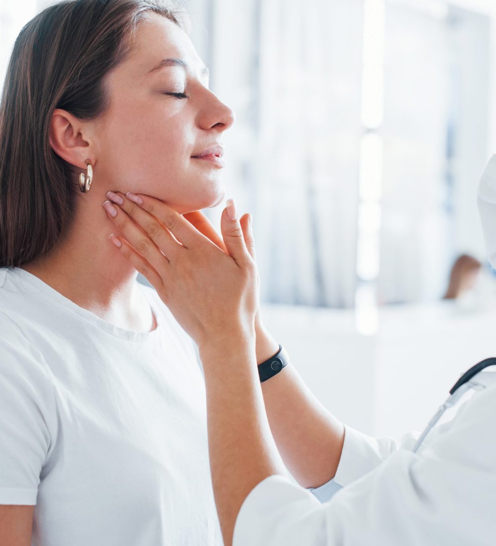 Checking lymph nodes and throat. Young woman have a visit with female doctor in modern clinic.